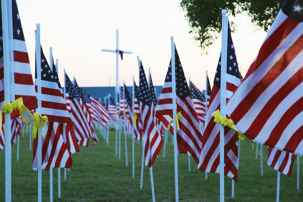 Image of USA flags and the cross in the distance